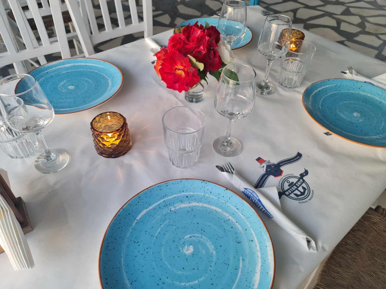 O masă pregătită cu farfurii albastre și trandafiri la Taverna Motorship